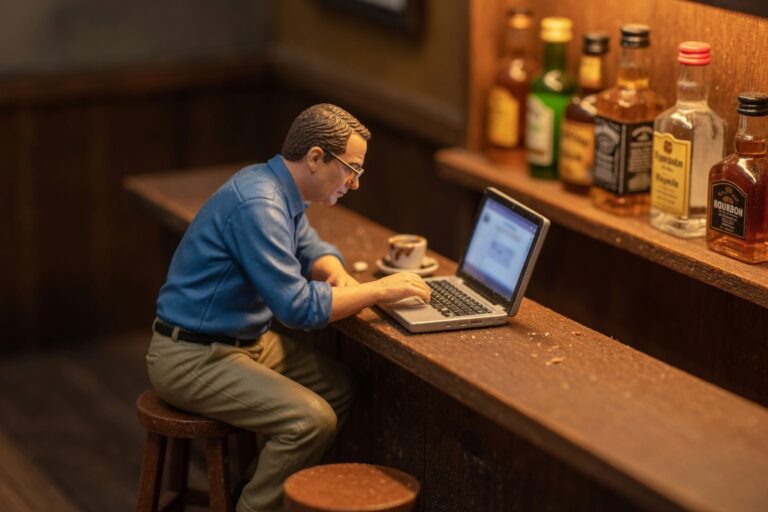 Miniature figure taking alcohol training on a laptop